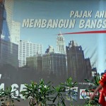 Warga melintas di depan papan iklan Pajak, Jakarta. (JG Photo/Afriadi Hikmal)