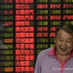 An investor stands in front of electronic board showing stock information at a brokerage house in Shanghai